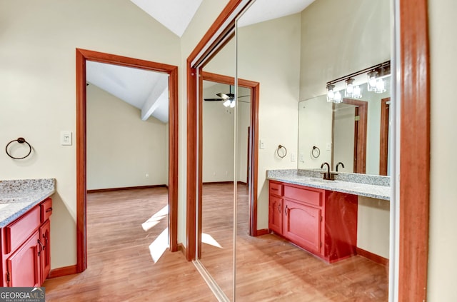 bathroom featuring ceiling fan, vaulted ceiling, vanity, and wood finished floors