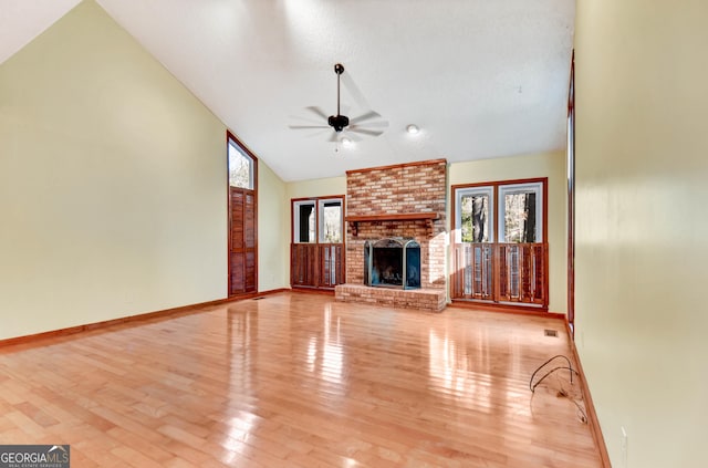 unfurnished living room featuring ceiling fan, high vaulted ceiling, wood finished floors, baseboards, and a brick fireplace