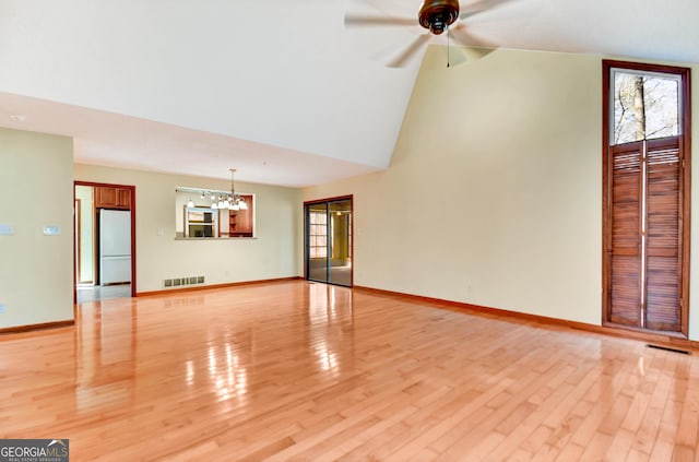 unfurnished living room featuring light wood-type flooring, visible vents, baseboards, and ceiling fan with notable chandelier