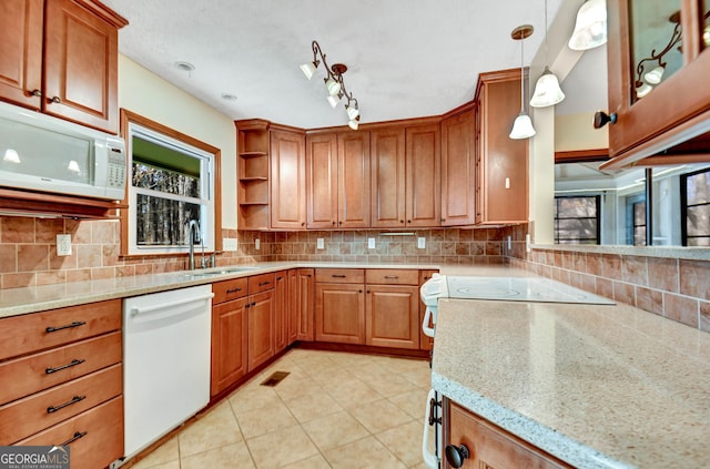 kitchen featuring white appliances, brown cabinets, a sink, and backsplash