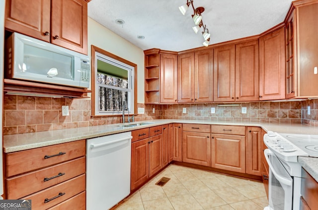 kitchen featuring visible vents, decorative backsplash, brown cabinetry, a sink, and white appliances