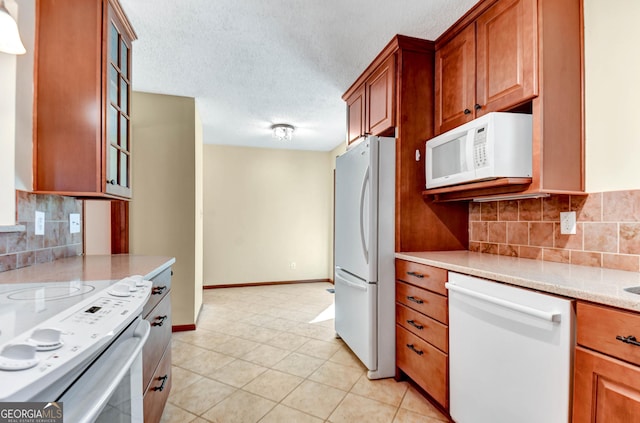 kitchen with white appliances, glass insert cabinets, brown cabinets, and a textured ceiling