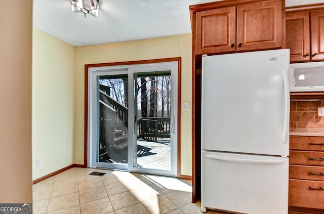 doorway to outside featuring visible vents, a textured ceiling, baseboards, and light tile patterned floors