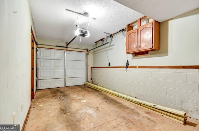 garage with concrete block wall and a garage door opener