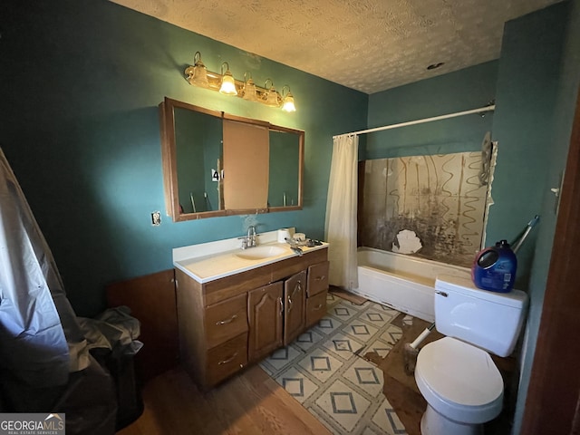 bathroom with a textured ceiling, shower / bath combo, vanity, and toilet