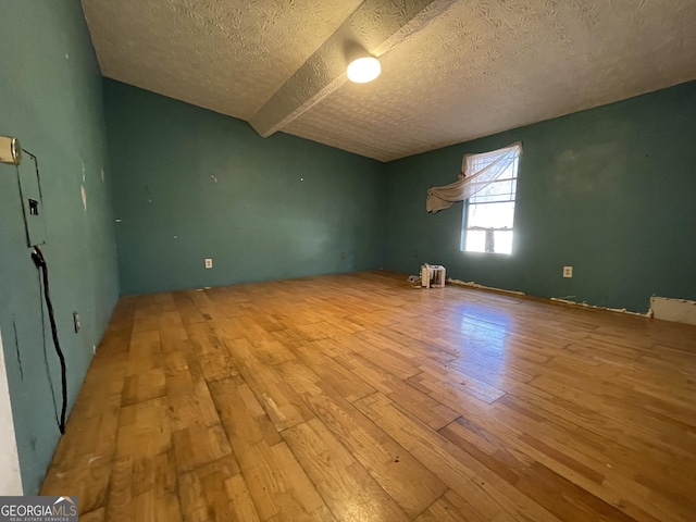 unfurnished room featuring hardwood / wood-style flooring and a textured ceiling