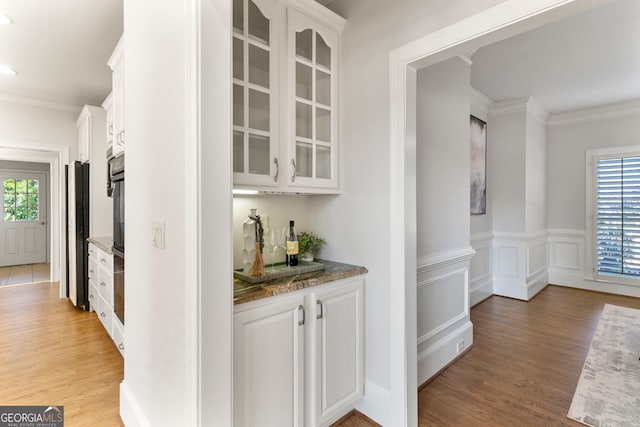 bar featuring light wood-type flooring, a wealth of natural light, and crown molding