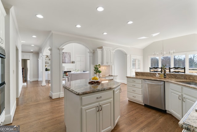 kitchen featuring wood finished floors, a kitchen island, white cabinets, stainless steel dishwasher, and decorative backsplash