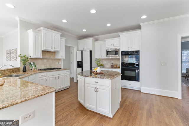 kitchen featuring light stone counters, a sink, ornamental molding, and built in appliances