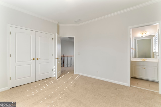 unfurnished bedroom featuring carpet, crown molding, a closet, ensuite bathroom, and baseboards