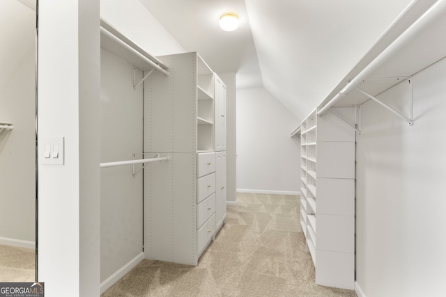 walk in closet with light carpet and vaulted ceiling