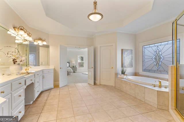 ensuite bathroom featuring a tray ceiling, tile patterned flooring, a garden tub, and vanity