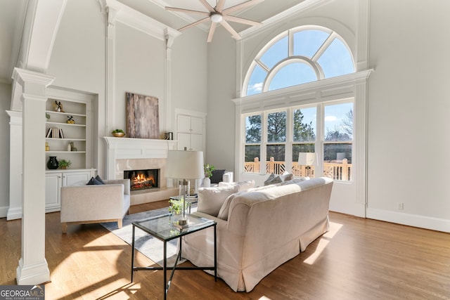 living room with baseboards, a premium fireplace, wood finished floors, and ornate columns