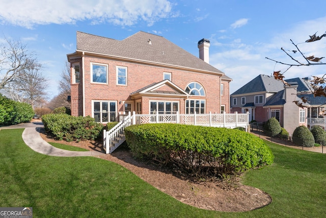 back of house featuring brick siding, a lawn, and a chimney