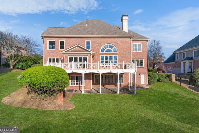 back of house with a patio, a chimney, fence, a yard, and brick siding