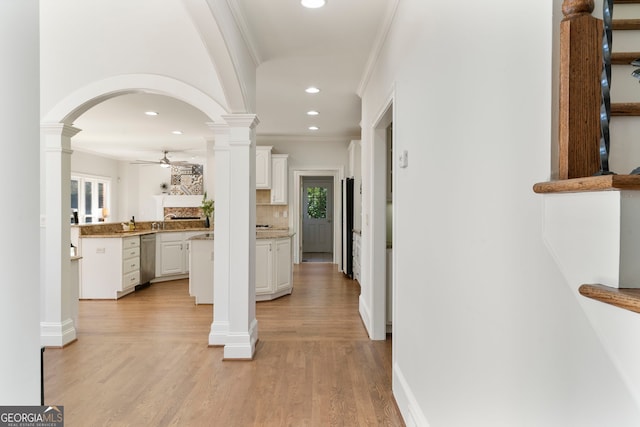 hallway with light wood-type flooring, decorative columns, ornamental molding, and recessed lighting