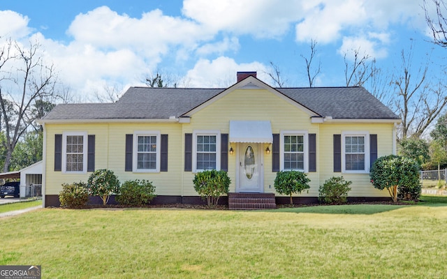 view of front of house featuring roof with shingles, a chimney, and a front yard