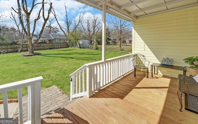 wooden terrace featuring a lawn and fence