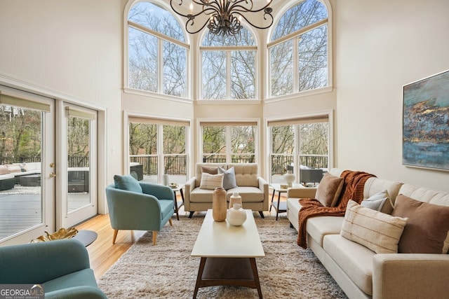 living area with wood finished floors, a towering ceiling, and a notable chandelier