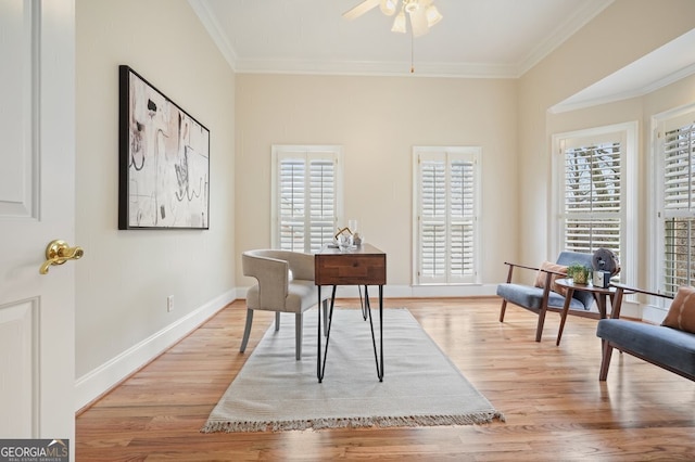 office space with light wood-style floors, baseboards, ornamental molding, and a ceiling fan