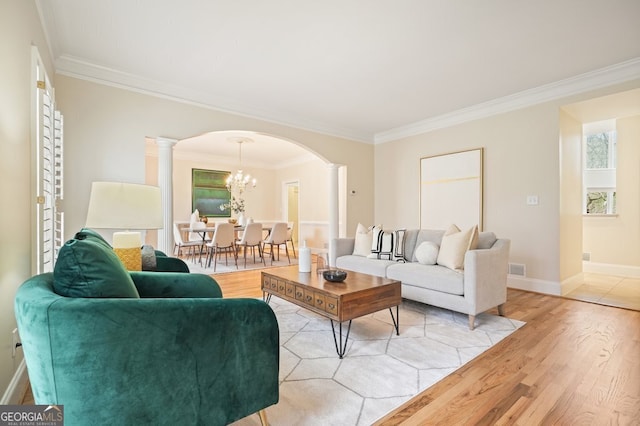 living room with arched walkways, decorative columns, light wood-style flooring, and crown molding