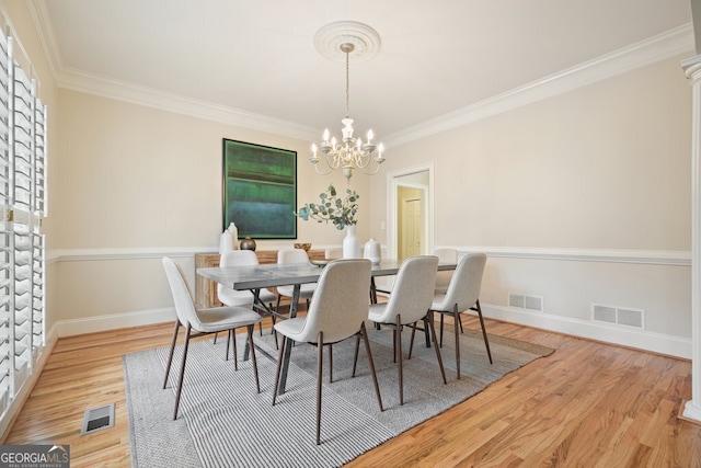 dining room with visible vents, crown molding, and wood finished floors