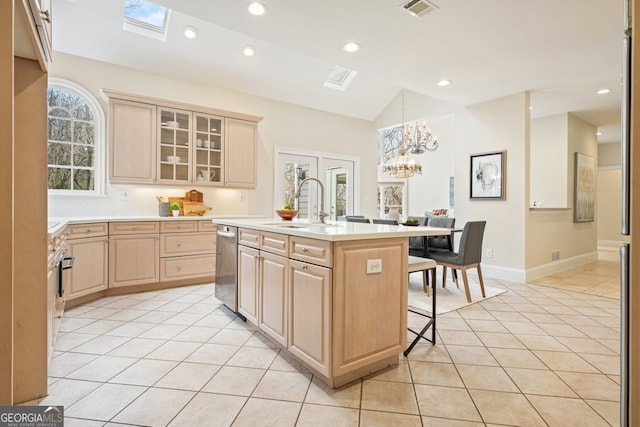 kitchen featuring light tile patterned floors, a kitchen breakfast bar, light countertops, dishwasher, and light brown cabinetry