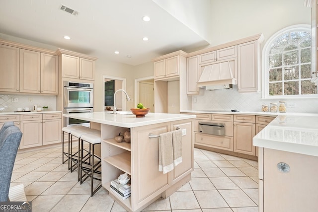 kitchen with light tile patterned floors, double oven, premium range hood, and visible vents