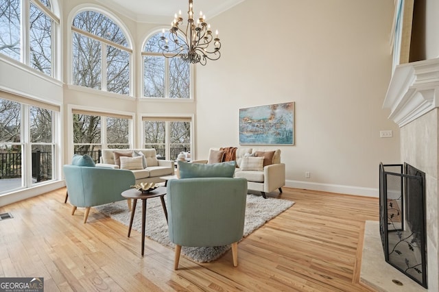 living room with ornamental molding, a high end fireplace, a healthy amount of sunlight, and light wood-style flooring