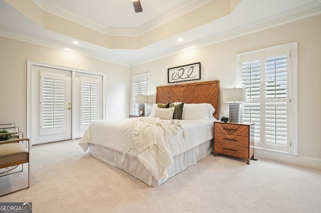 bedroom with access to exterior, multiple windows, a tray ceiling, and carpet flooring