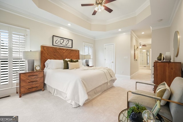 bedroom featuring light carpet, baseboards, visible vents, a tray ceiling, and crown molding