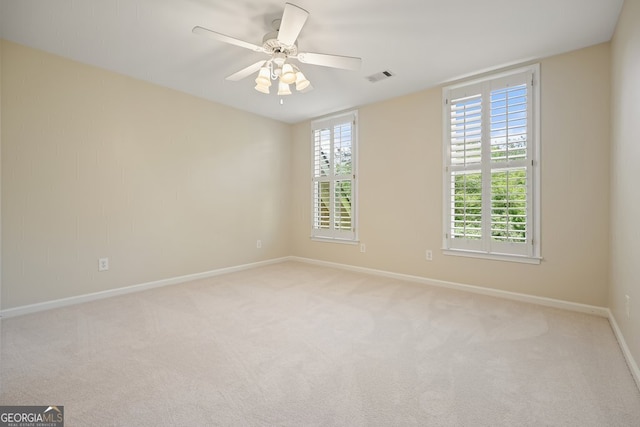 unfurnished room with carpet, visible vents, ceiling fan, and baseboards