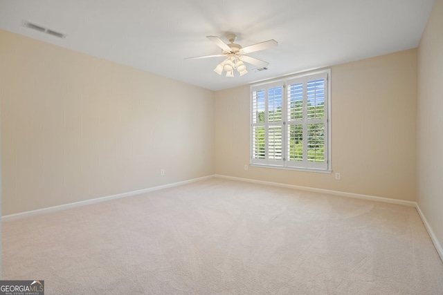 spare room with light carpet, baseboards, visible vents, and a ceiling fan