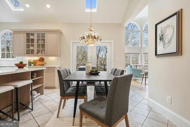 dining space featuring a skylight, light tile patterned floors, recessed lighting, a chandelier, and baseboards