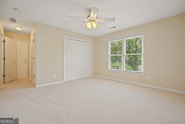 unfurnished bedroom with a closet, light carpet, visible vents, and baseboards