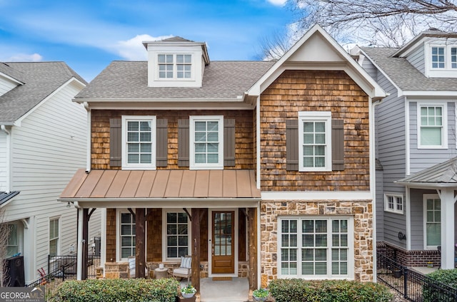 view of property featuring stone siding, a shingled roof, a porch, and fence