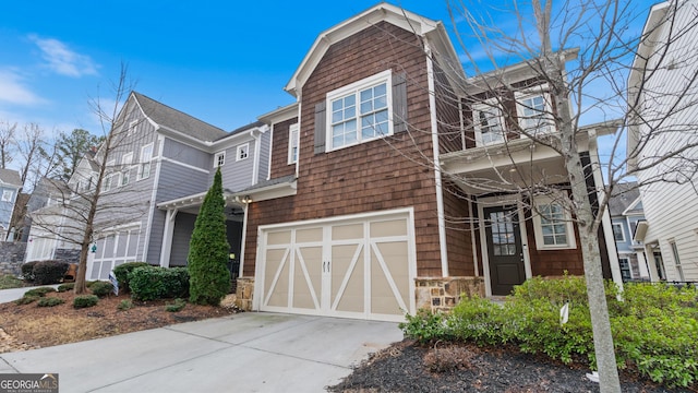 view of front of home featuring an attached garage, stone siding, and concrete driveway