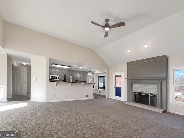 unfurnished living room with lofted ceiling, ceiling fan, carpet floors, a fireplace, and baseboards