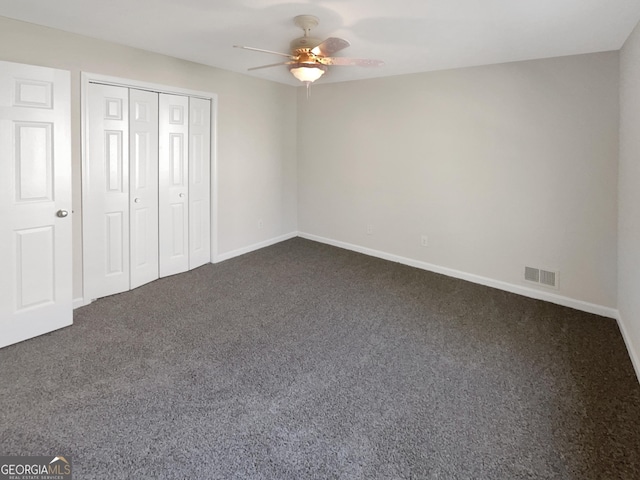 unfurnished bedroom with dark colored carpet, a closet, visible vents, and baseboards