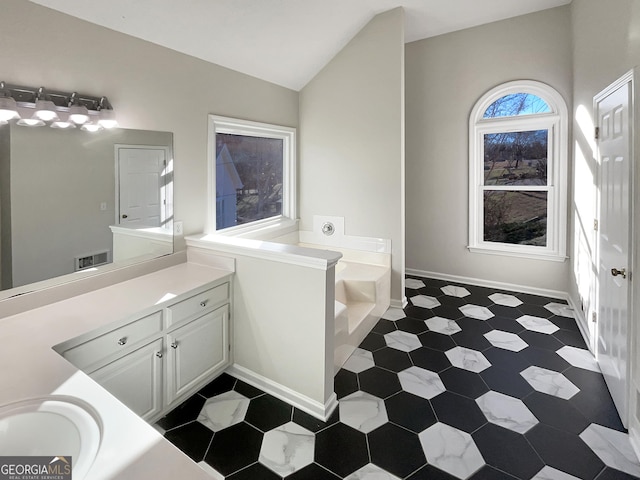 bathroom featuring lofted ceiling, baseboards, a bath, and vanity