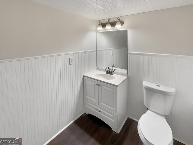 bathroom with toilet, a wainscoted wall, wood finished floors, and vanity