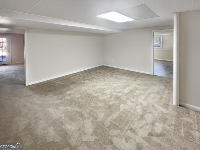 basement with a drop ceiling, carpet flooring, and baseboards