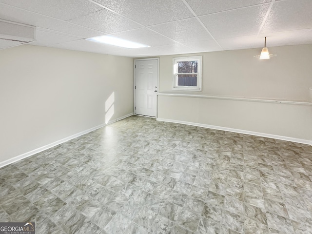 basement featuring a drop ceiling, tile patterned floors, and baseboards