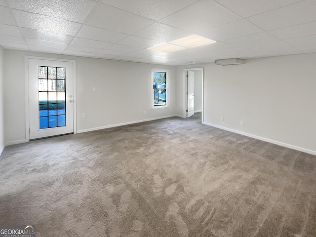 empty room with carpet floors, a paneled ceiling, and a healthy amount of sunlight