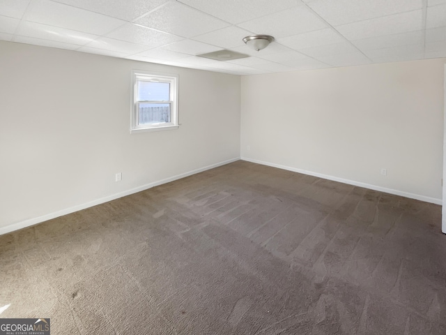 unfurnished room featuring baseboards, dark carpet, and a drop ceiling