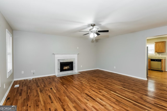 unfurnished living room with a fireplace, wood finished floors, visible vents, and baseboards