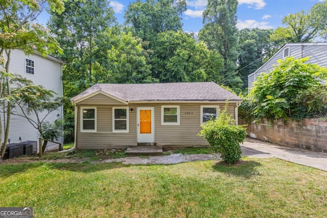 view of front of house with roof with shingles and a front yard