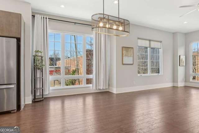 unfurnished dining area featuring dark wood-type flooring, baseboards, and a ceiling fan