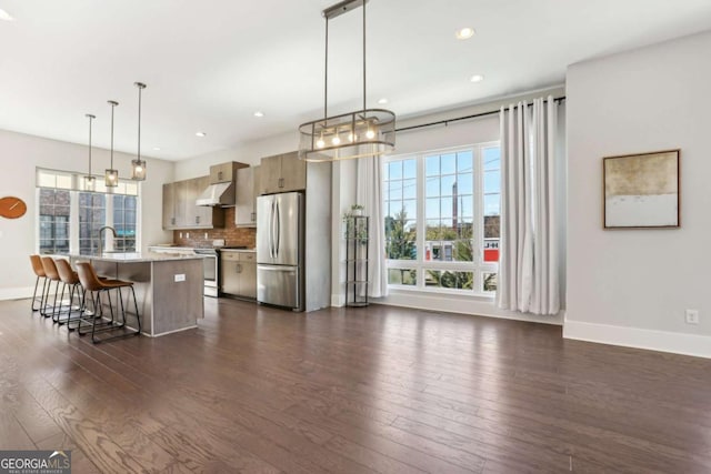 kitchen featuring stainless steel appliances, dark wood finished floors, under cabinet range hood, and decorative backsplash