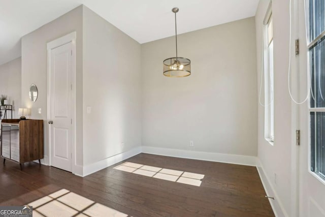 spare room featuring a healthy amount of sunlight, baseboards, and hardwood / wood-style floors